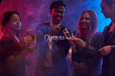 Salle de réception avec piste de danse, éclairage violet, équipement audio et décoration florale.