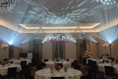 Salle de réception avec piste de danse, éclairage violet, équipement audio et décoration florale.