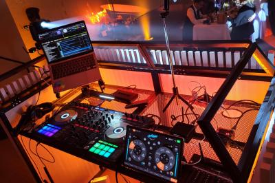 Salle de réception avec piste de danse, éclairage violet, équipement audio et décoration florale.