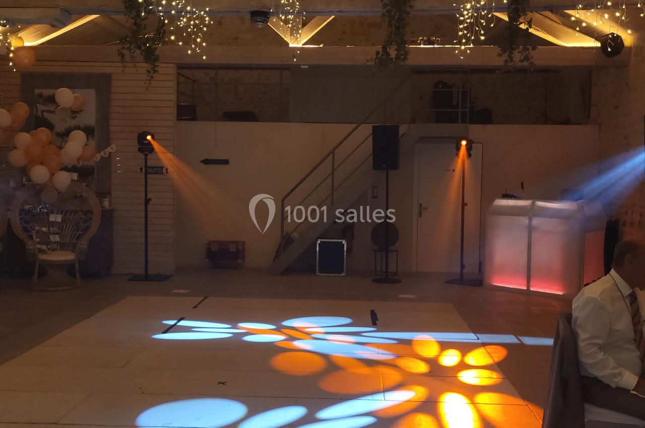 Salle de réception décorée avec des guirlandes lumineuses, des ballons et un éclairage coloré projeté au sol.