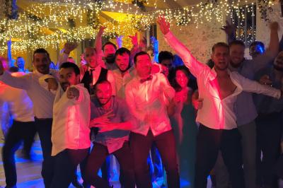 Salle de réception avec piste de danse, éclairage violet, équipement audio et décoration florale.