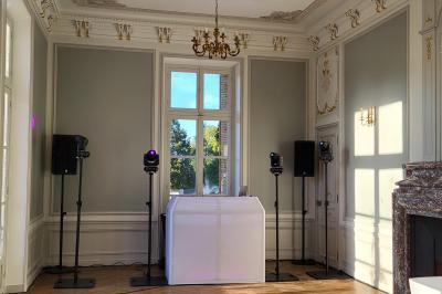 Salle de réception avec piste de danse, éclairage violet, équipement audio et décoration florale.