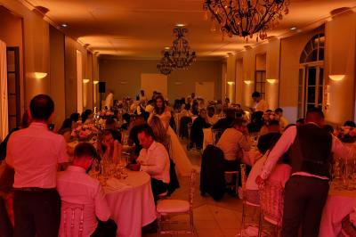 Salle de réception avec piste de danse, éclairage violet, équipement audio et décoration florale.