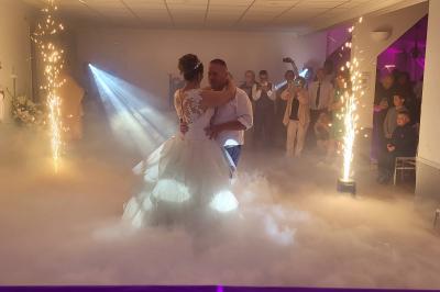 Salle de réception avec piste de danse, éclairage violet, équipement audio et décoration florale.