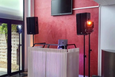 Installation de matériel audiovisuel avec éclairage violet, devant un mur décoré de fleurs blanches.