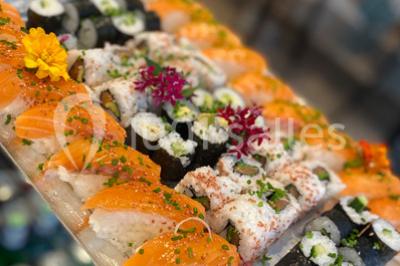 Atelier culinaire avec préparation de sushis et makis, ingrédients frais et ustensiles disposés sur une table.