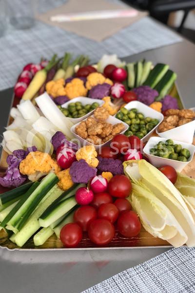 Plateau de crudités colorées avec tomates cerises, radis, concombres, choux-fleurs, endives et petits pois.