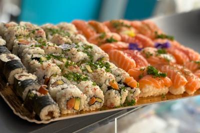 Atelier culinaire avec préparation de sushis et makis, ingrédients frais et ustensiles disposés sur une table.