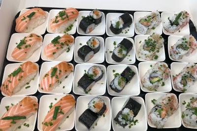 Atelier culinaire avec préparation de sushis et makis, ingrédients frais et ustensiles disposés sur une table.