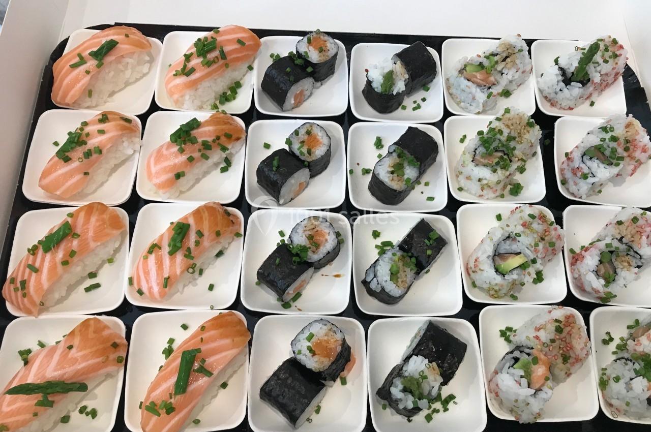 Plateau de sushis variés disposés sur des assiettes individuelles, comprenant nigiris au saumon et makis garnis.