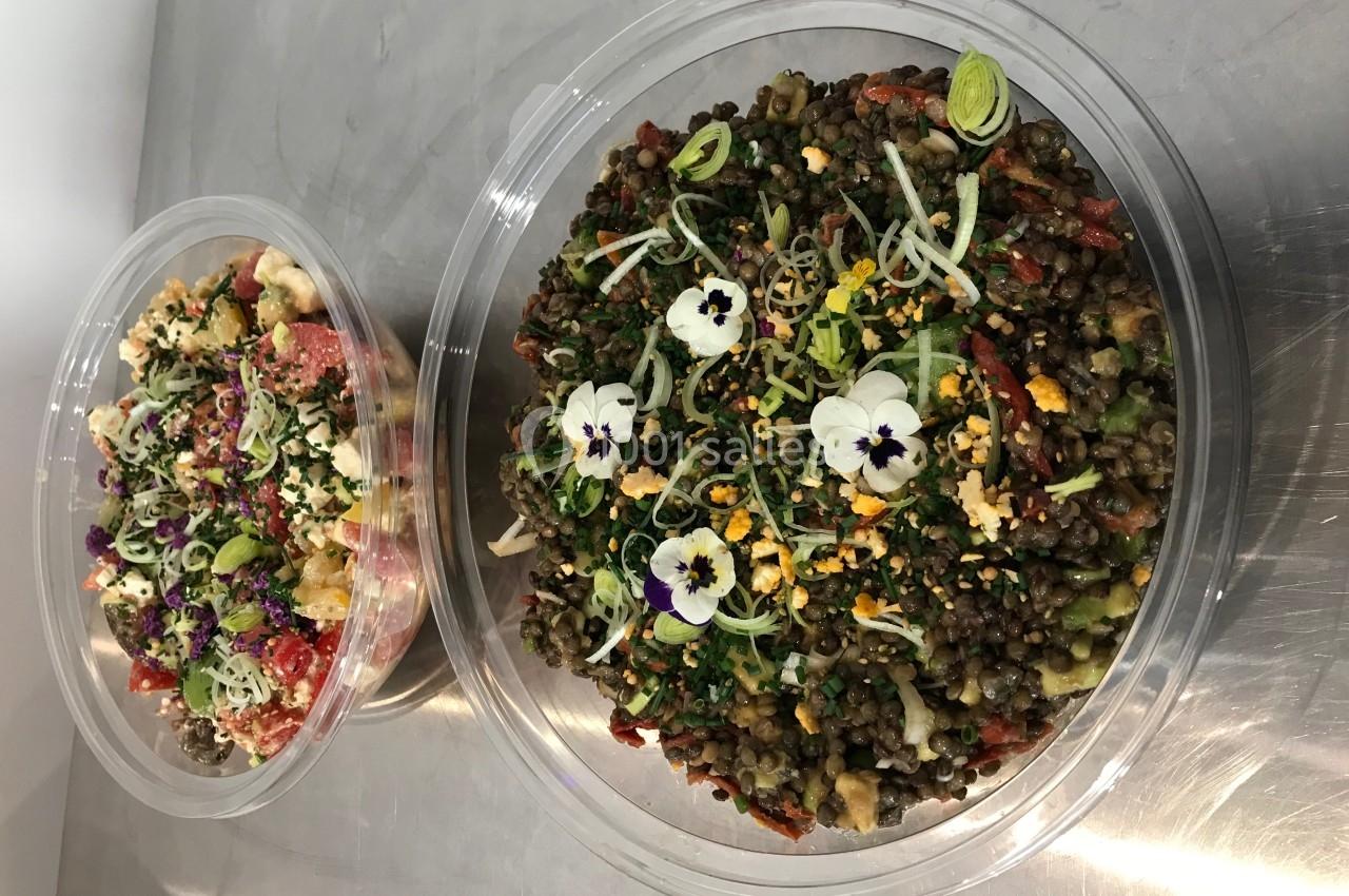 Deux salades colorées dans des bols transparents, garnies de fleurs comestibles et présentées sur une surface métallique.