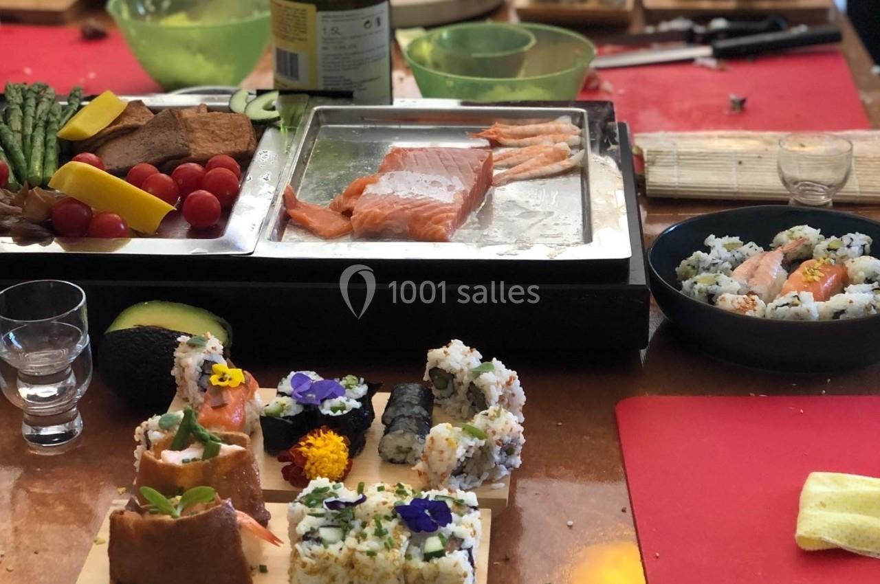 Atelier culinaire avec préparation de sushis et makis, ingrédients frais et ustensiles disposés sur une table.