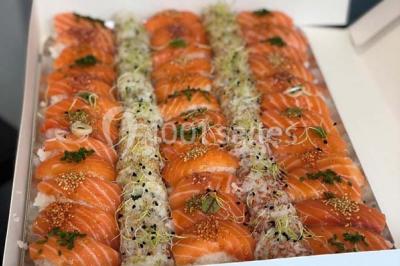 Personnes préparant des sushis autour d'une table avec des bols, ingrédients et ustensiles de cuisine.