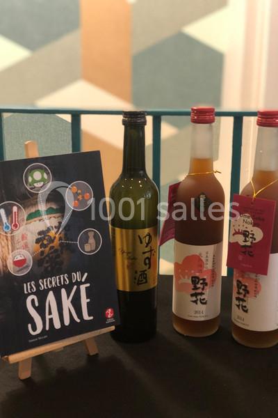 Trois bouteilles de saké et un livret intitulé ’Les secrets du saké’ exposés sur une table.