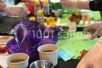 Personnes préparant des sushis autour d'une table avec des bols, ingrédients et ustensiles de cuisine.