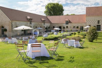 Grand bâtiment classique entouré d'une pelouse bien entretenue, avec un arbre imposant et un petit bassin au premier plan.