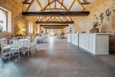 Grand bâtiment classique entouré d'une pelouse bien entretenue, avec un arbre imposant et un petit bassin au premier plan.