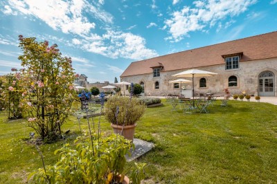 Grand bâtiment classique entouré d'une pelouse bien entretenue, avec un arbre imposant et un petit bassin au premier plan.