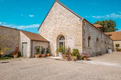 Grand bâtiment classique entouré d'une pelouse bien entretenue, avec un arbre imposant et un petit bassin au premier plan.