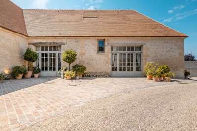 Grand bâtiment classique entouré d'une pelouse bien entretenue, avec un arbre imposant et un petit bassin au premier plan.