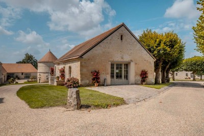 Grand bâtiment classique entouré d'une pelouse bien entretenue, avec un arbre imposant et un petit bassin au premier plan.
