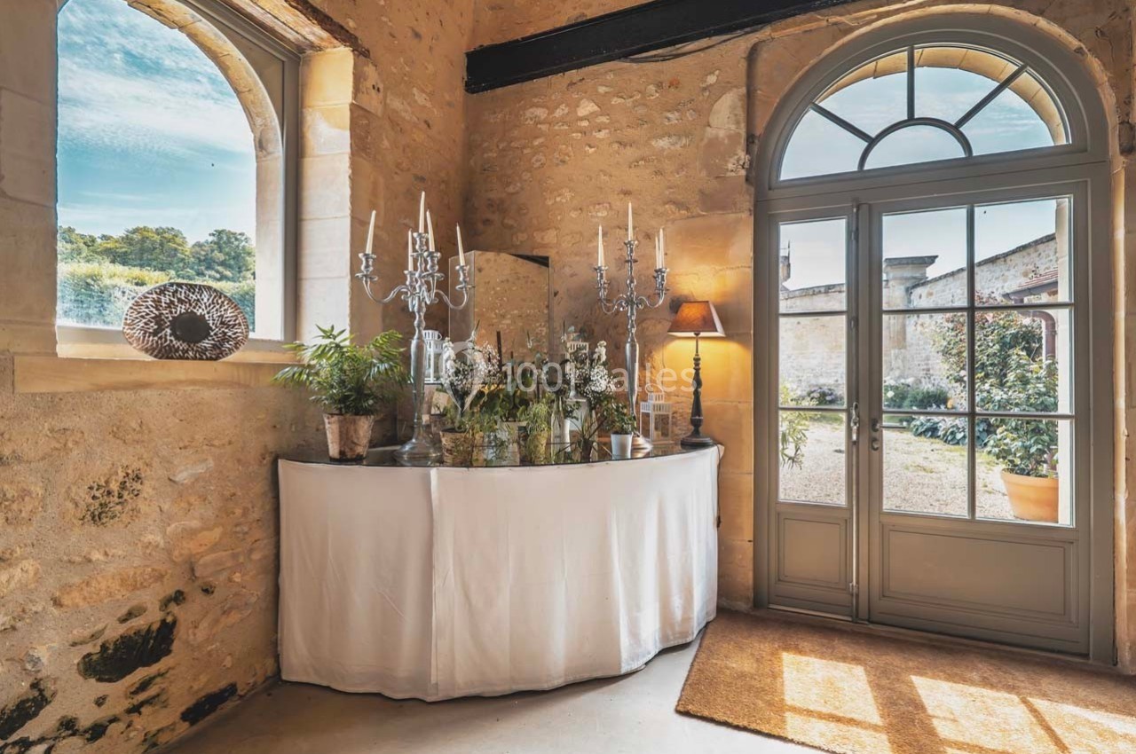 Buffet décoré avec des plantes et des chandeliers dans une pièce en pierre lumineuse avec de grandes fenêtres.