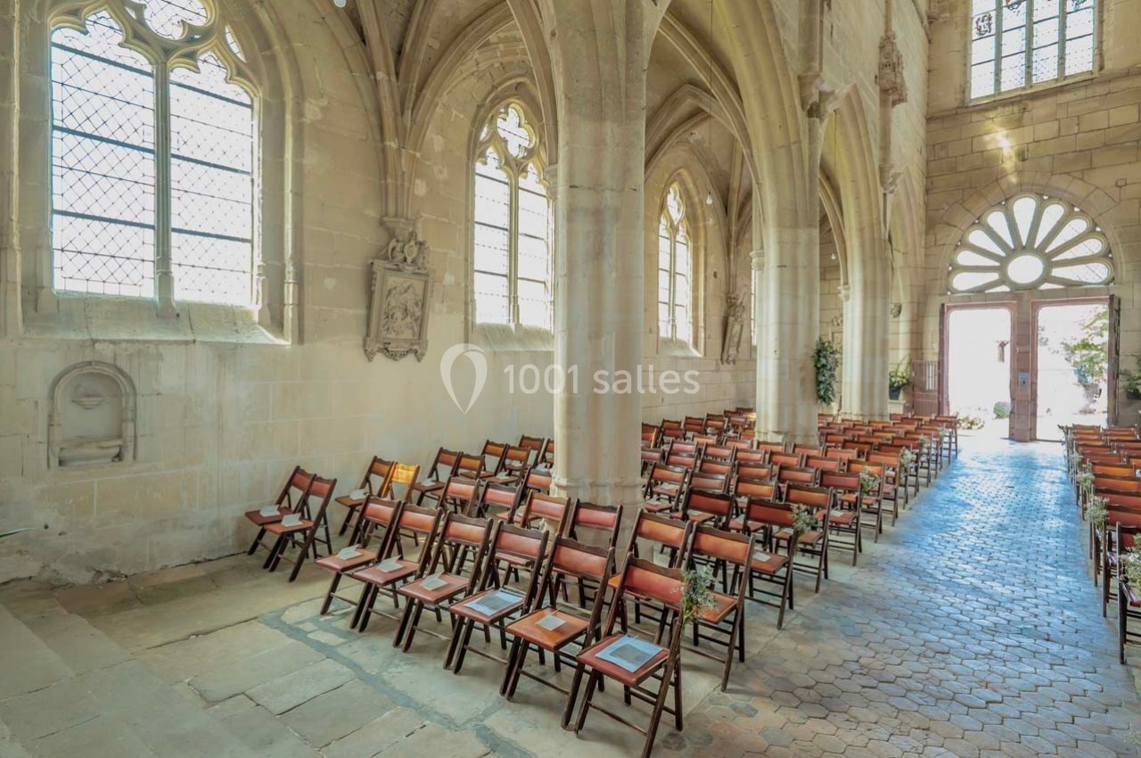 Intérieur d'une église avec des rangées de chaises en bois alignées sous des voûtes et des vitraux.
