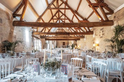 Petit pont en pierre surplombant un chemin, entouré de verdure et jouxtant un bâtiment ancien avec toiture en ardoise.
