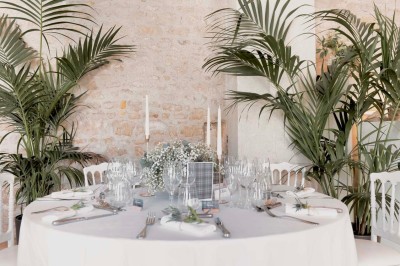 Petit pont en pierre surplombant un chemin, entouré de verdure et jouxtant un bâtiment ancien avec toiture en ardoise.