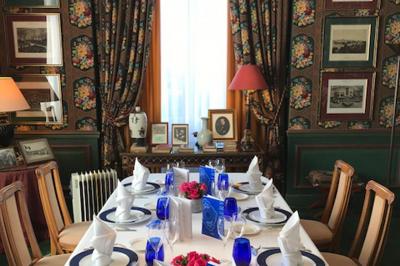 Table élégamment dressée avec vaisselle à motifs bleus, bouquet de fleurs au centre, dans une salle lumineuse et raffinée.