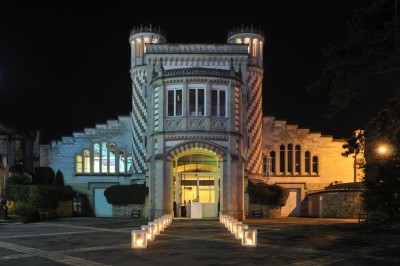 Salle voûtée décorée avec des tables rondes dressées pour un événement, éclairée par des lumières violettes.
