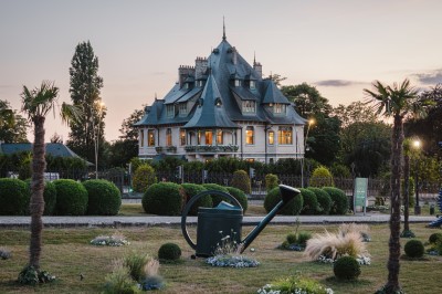 Salle voûtée décorée avec des tables rondes dressées pour un événement, éclairée par des lumières violettes.