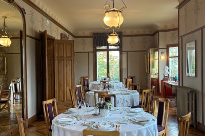 Salle voûtée décorée avec des tables rondes dressées pour un événement, éclairée par des lumières violettes.