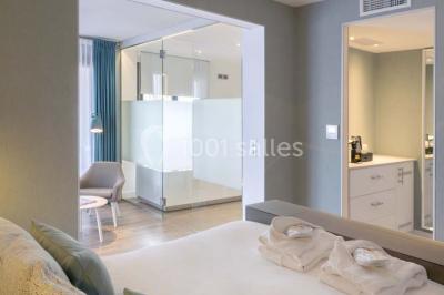 Chambre lumineuse avec lit double, papier peint à motifs de flamants roses, mobilier moderne et télévision murale.