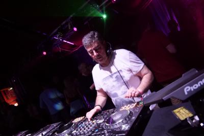 Un DJ mixe sur scène dans une ambiance sombre et lumineuse, décorée avec des éléments d'Halloween.