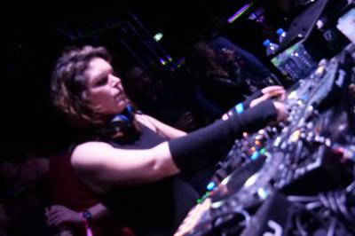 Un DJ mixe sur scène dans une ambiance sombre et lumineuse, décorée avec des éléments d'Halloween.