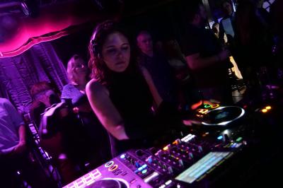 Un DJ mixe sur scène dans une ambiance sombre et lumineuse, décorée avec des éléments d'Halloween.