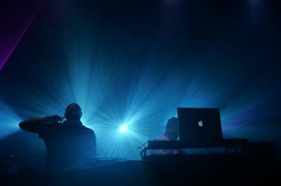 Un DJ mixe sur scène dans une ambiance sombre et lumineuse, décorée avec des éléments d'Halloween.