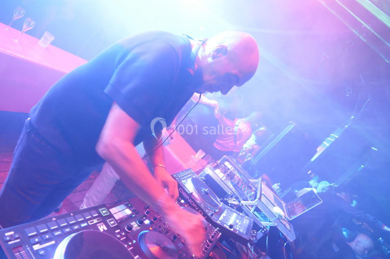 Un DJ mixant de la musique sur des platines dans une ambiance lumineuse de soirée avec des effets de fumée.