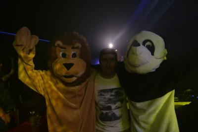 Un DJ mixe sur scène dans une ambiance sombre et lumineuse, décorée avec des éléments d'Halloween.