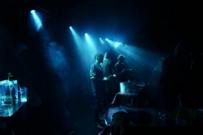 Un DJ mixe sur scène dans une ambiance sombre et lumineuse, décorée avec des éléments d'Halloween.