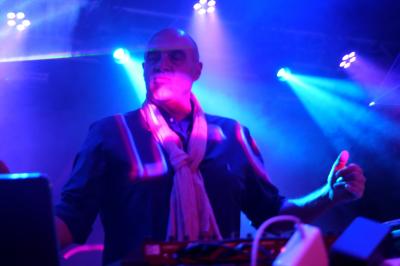 Un DJ mixe sur scène dans une ambiance sombre et lumineuse, décorée avec des éléments d'Halloween.