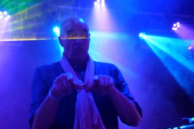 Un DJ mixe sur scène dans une ambiance sombre et lumineuse, décorée avec des éléments d'Halloween.