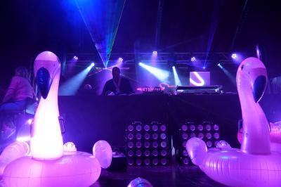 Un DJ mixe sur scène dans une ambiance sombre et lumineuse, décorée avec des éléments d'Halloween.