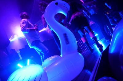 Un DJ mixe sur scène dans une ambiance sombre et lumineuse, décorée avec des éléments d'Halloween.