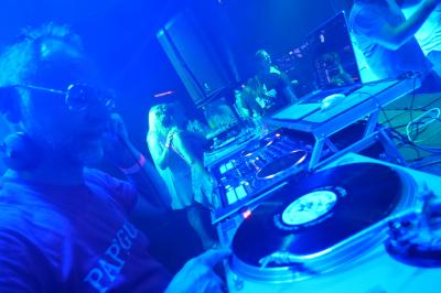 Un DJ mixe sur scène dans une ambiance sombre et lumineuse, décorée avec des éléments d'Halloween.