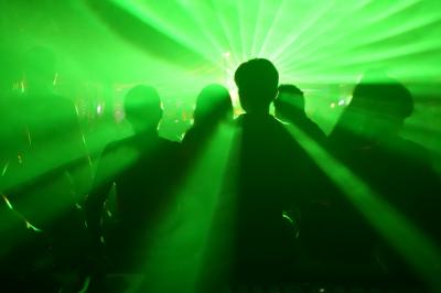 Un DJ mixe sur scène dans une ambiance sombre et lumineuse, décorée avec des éléments d'Halloween.