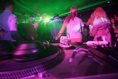 Un DJ mixe sur scène dans une ambiance sombre et lumineuse, décorée avec des éléments d'Halloween.