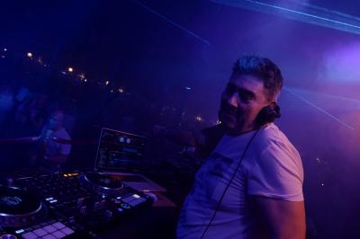 Un DJ mixe sur scène dans une ambiance sombre et lumineuse, décorée avec des éléments d'Halloween.