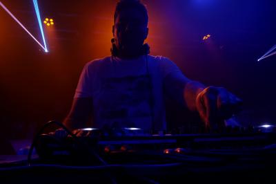 Un DJ mixe sur scène dans une ambiance sombre et lumineuse, décorée avec des éléments d'Halloween.